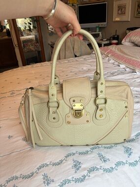 BCBGMaxAzria Cream Textured Satchel with Gold Hardware and lock buckle detail.